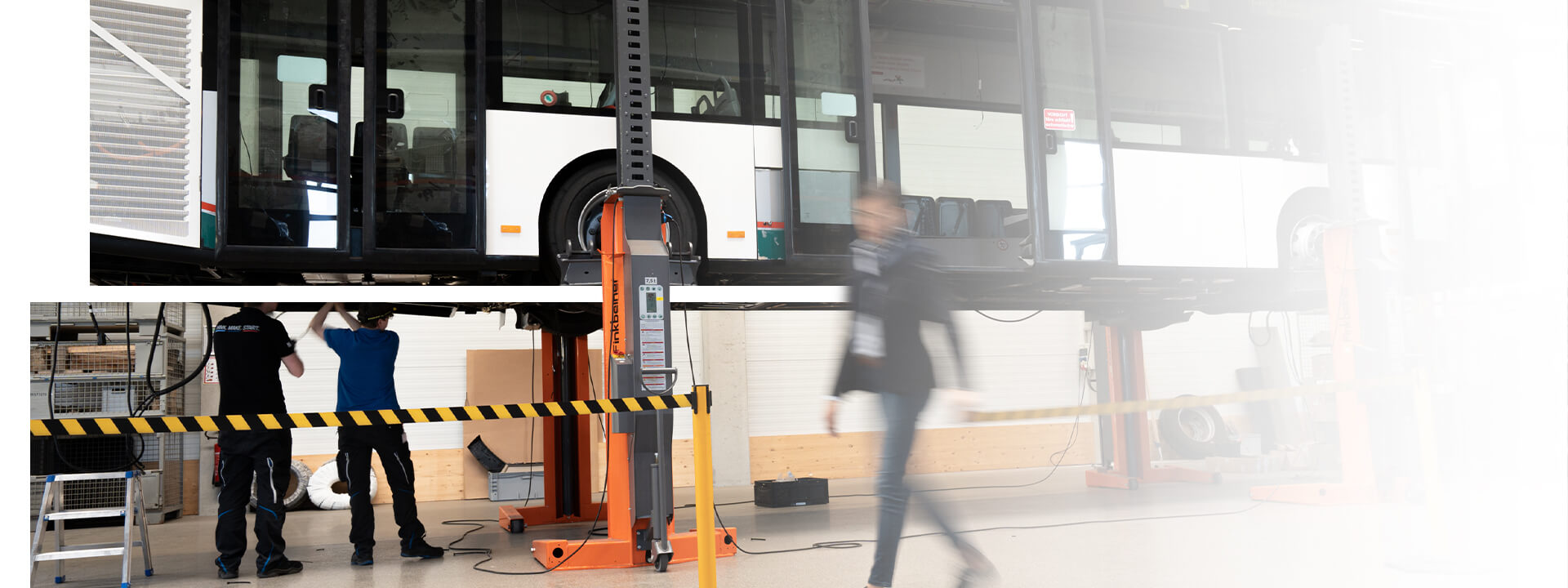 Eine Mitarbeiterin von pepper geht durch die Halle in der zwei Kollegen gerade an einem Bus die Verkabelung des Elektromotors einbauen.